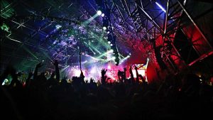 Mucha gente en un concierto con luces de colores y manos levantadas