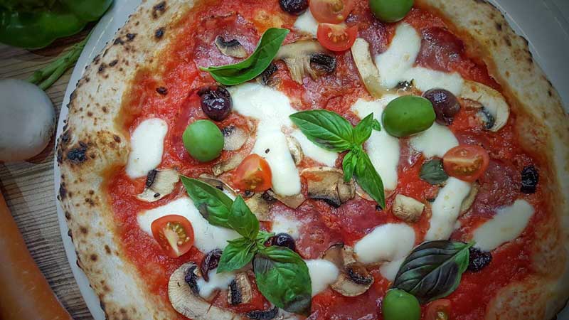 pizza capresa del restaurante con queso, tomate, albahaca, champiñones y aceitunas