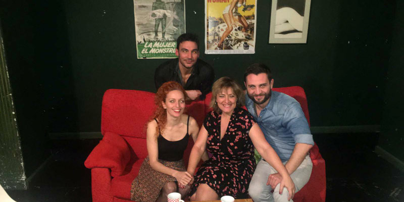 grupo de actores del teatro, sentados en sofá, mirando a cámara