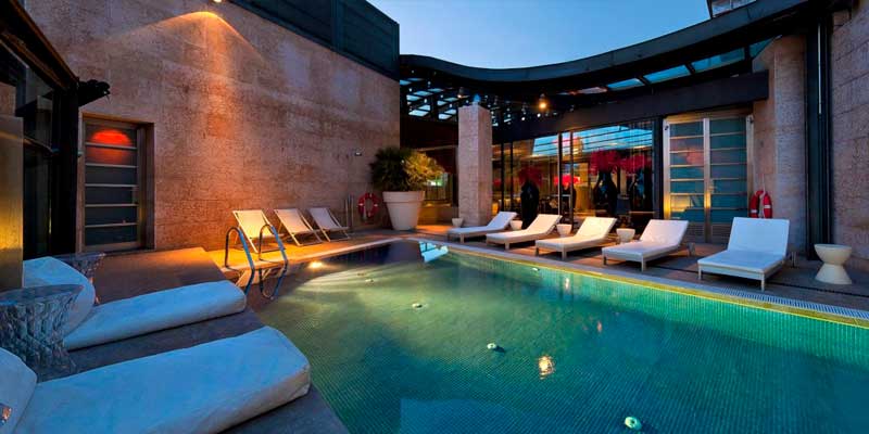piscina, con bancos y camas alrededor de la Terraza del Urban