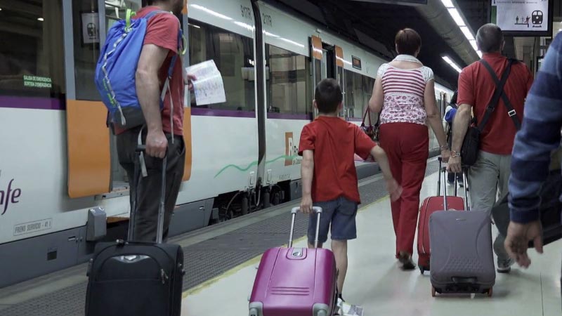 Turistas en una estación de tren con maletas