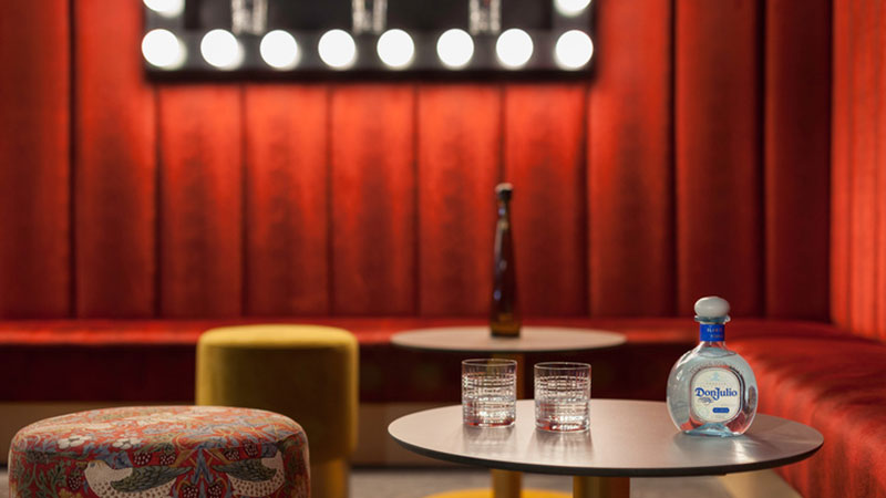 mesa con dos vasos y botellas de licor y luces de fondo