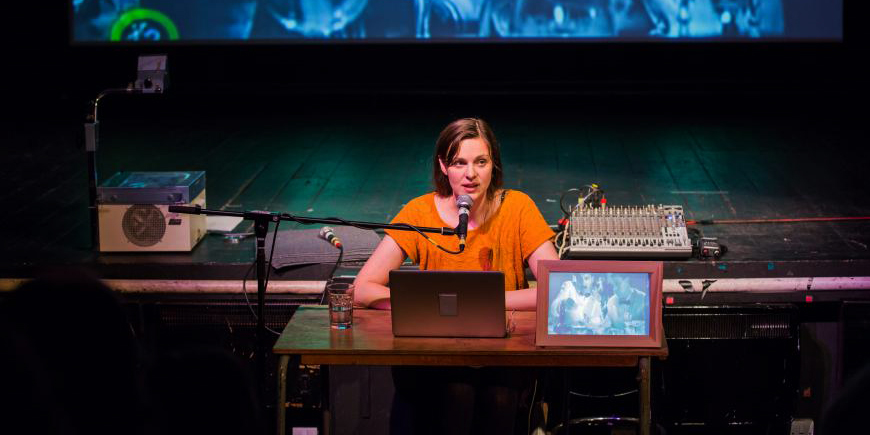 Deborah Pearson hablando en una mesa con un ordenador 