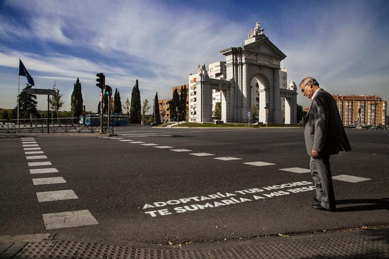 hombre leyendo un verso pintado en un paso de peatones
