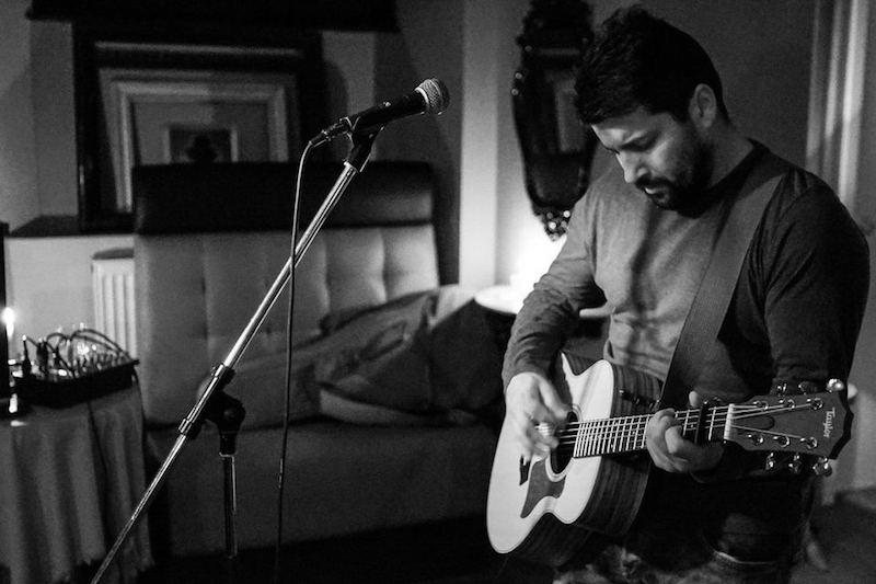 Ed Curtis tocando la guitarra y con micrófono en el salón
