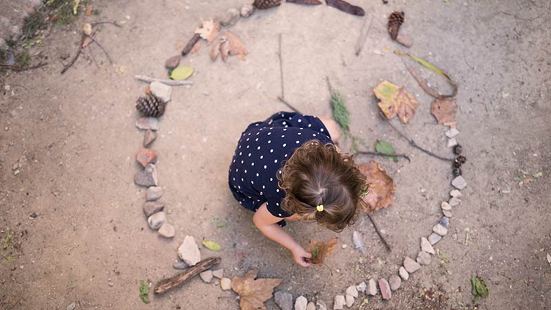 citas-4-malasaña Niña haciendo un mandala con piedras y ramas en el taller 'Mandalas en invierno'.