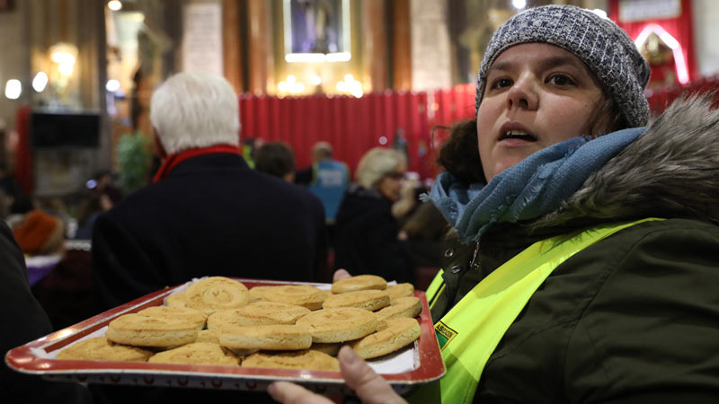 Mujer llevando una bandeja de panecillos de San Antón en la iglesia