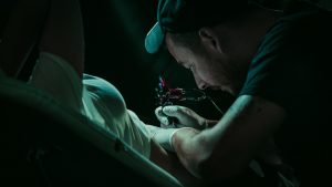Tatuador haciendo un tatuaje en el vientre a una mujer