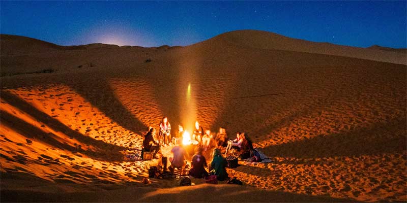 Personas alrededor de una hoguera en un desierto