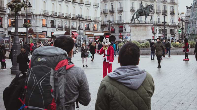 Pareja de turistas en la plaza de Sol en Madrid mirando a un personaje de dibujos