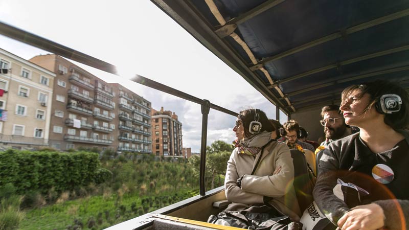 Dos mujeres con cascos puestos escuchando las indicaciones de la guía en el autobús de Imagina Madrid