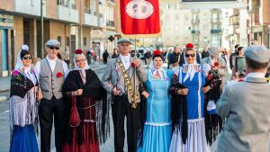 Grupo de gente mayor vestidos de chulapas y chulapos en medio de la calle haciéndose una foto con un móvil
