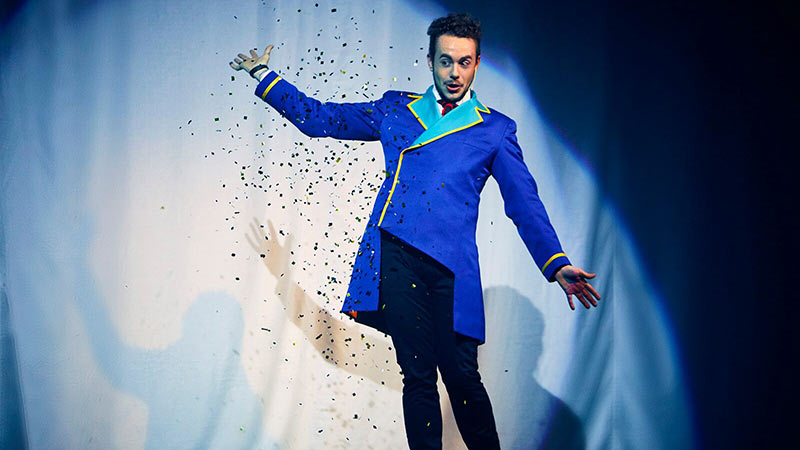 El Mago Marín abriendo su espectáculo vestido con una chaqueta larga azul y tirando confeti