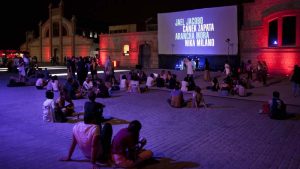 Gente sentada en un patio de Matadero disfrutando de los cortometrajes de la 1ª edición de ANIMARIO