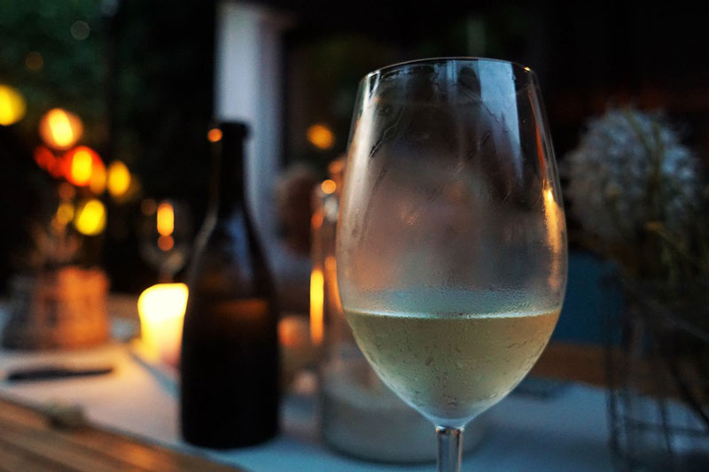 copa de vino blanco con una vela y una botella detrás- cata de vinos