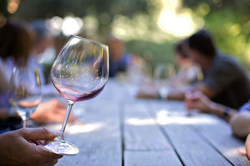 copa de cristal con vino en una mesa de madera con mucha gente-cata de vinos