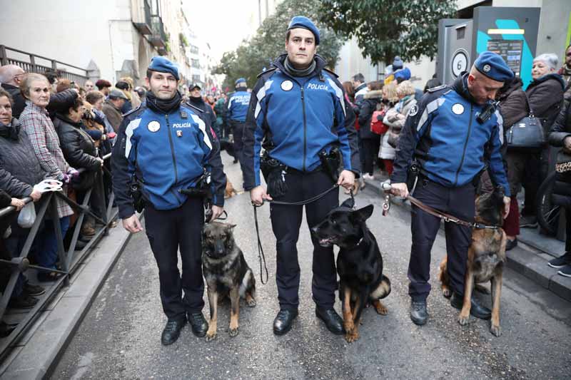 Tres policías con tres perros policía sentados y atados con una correa.