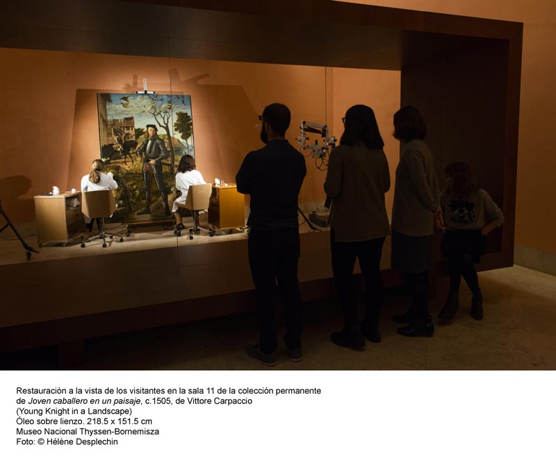 Varias personas viendo en el Museo Thyssen la restauración del cuadro 'Joven caballero en un paisaje' de Carpaccio