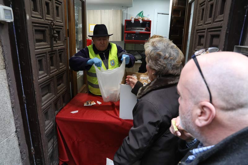 Un señor dando unos panecillos en una bolsa a una señora.