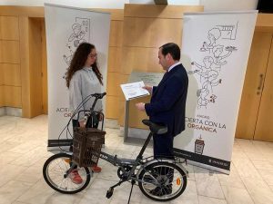 Un hombre le entrega un diploma y una bicicleta a una niña.