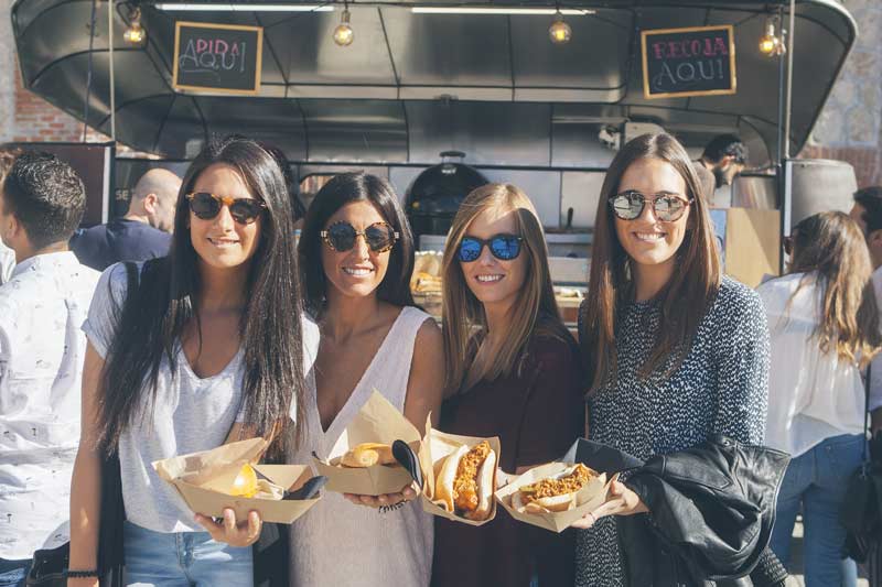 Cuatro mujeres con comida en la mano de los food trucks de Femme Creators.