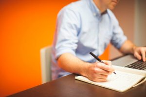 hombre con una libreta consultado un ordenador
